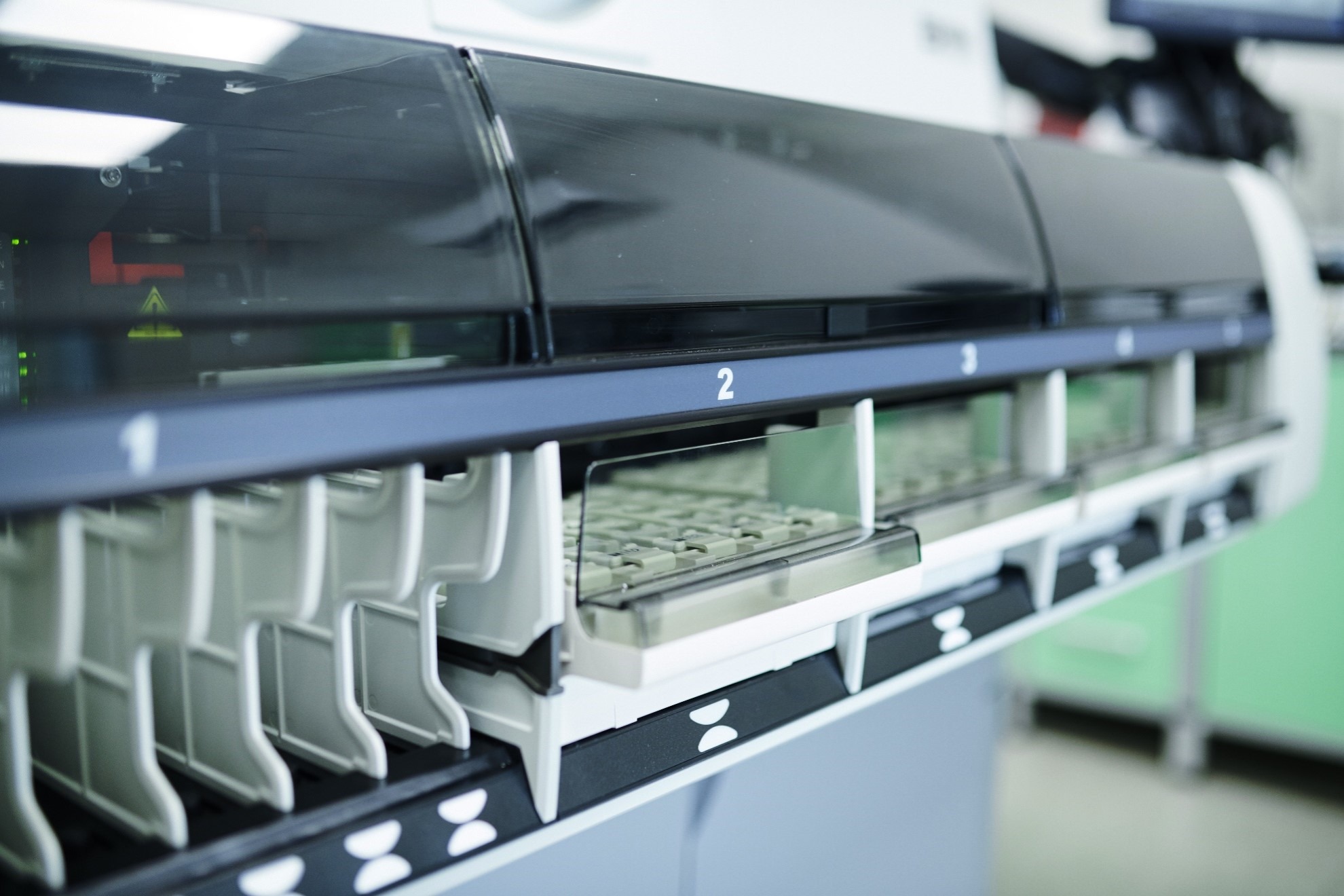 Automated sample analysis system with numbered compartments for pharmaceutical or biotech laboratory workflows.